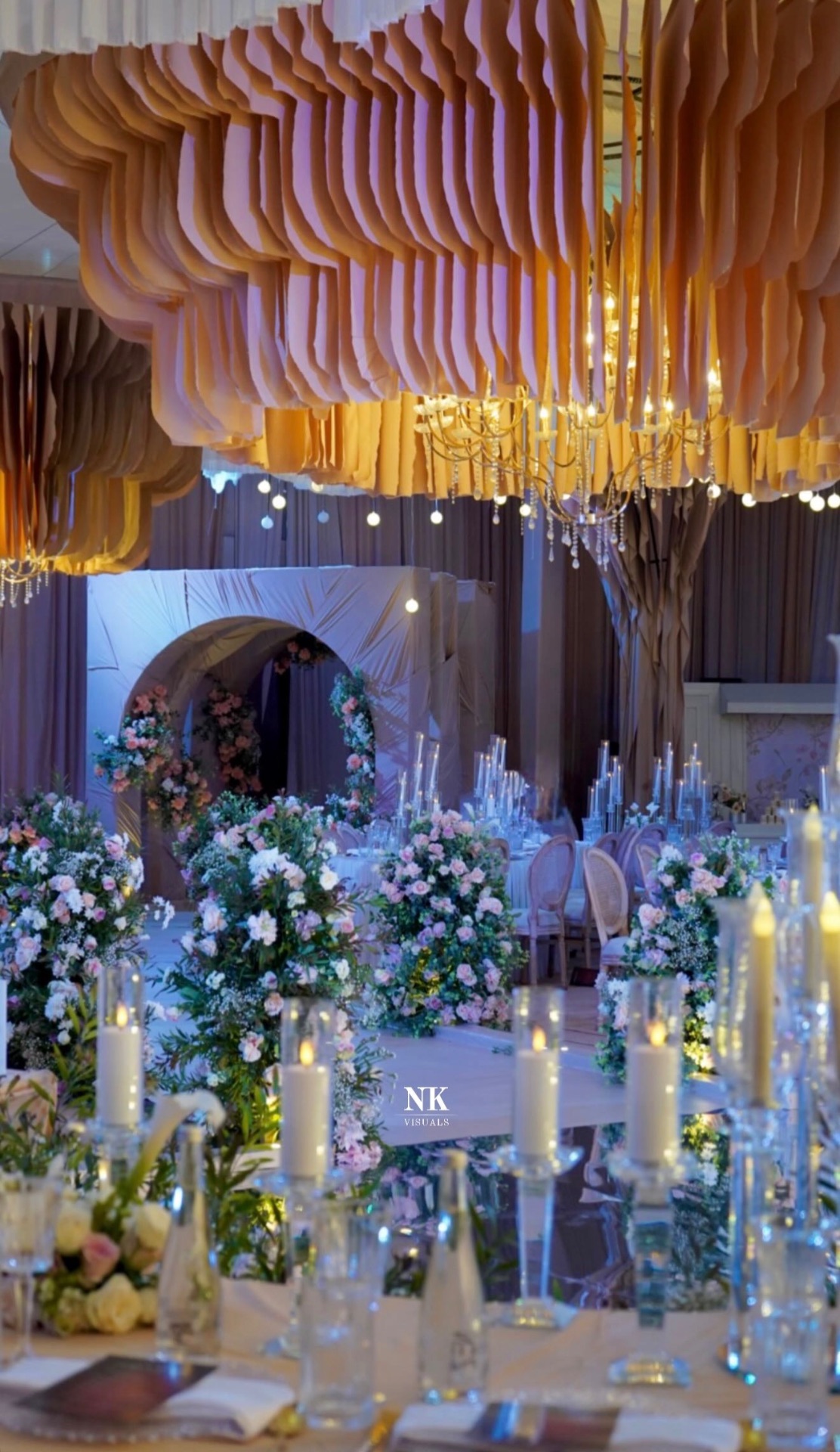 Reception hall with layered paper ceiling, chandeliers, florals and candles