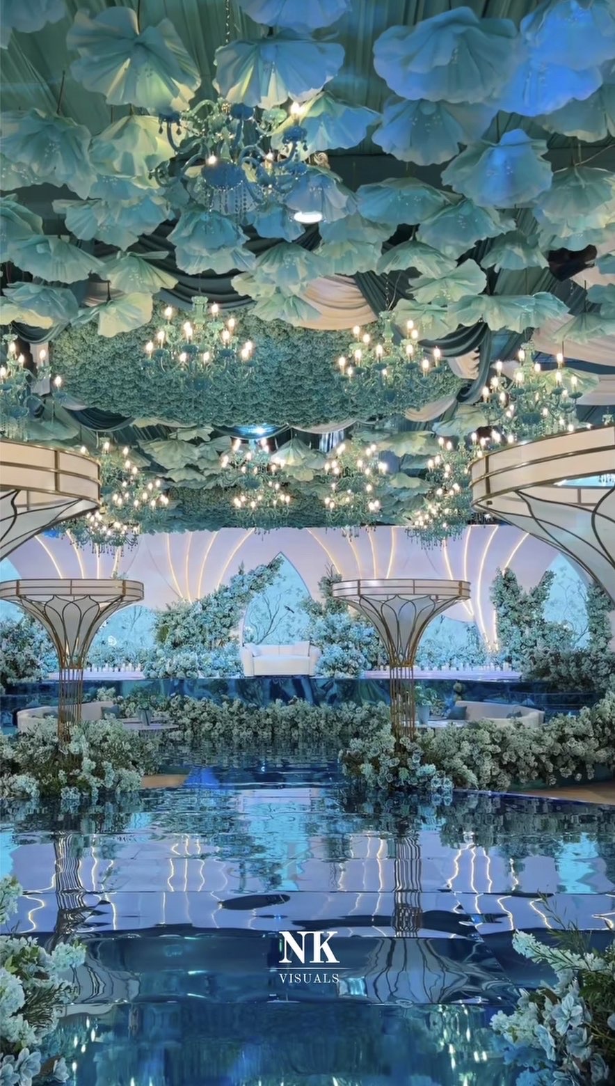 Wedding hall dressed in pale blue florals, chandeliers and a mirrored aisle