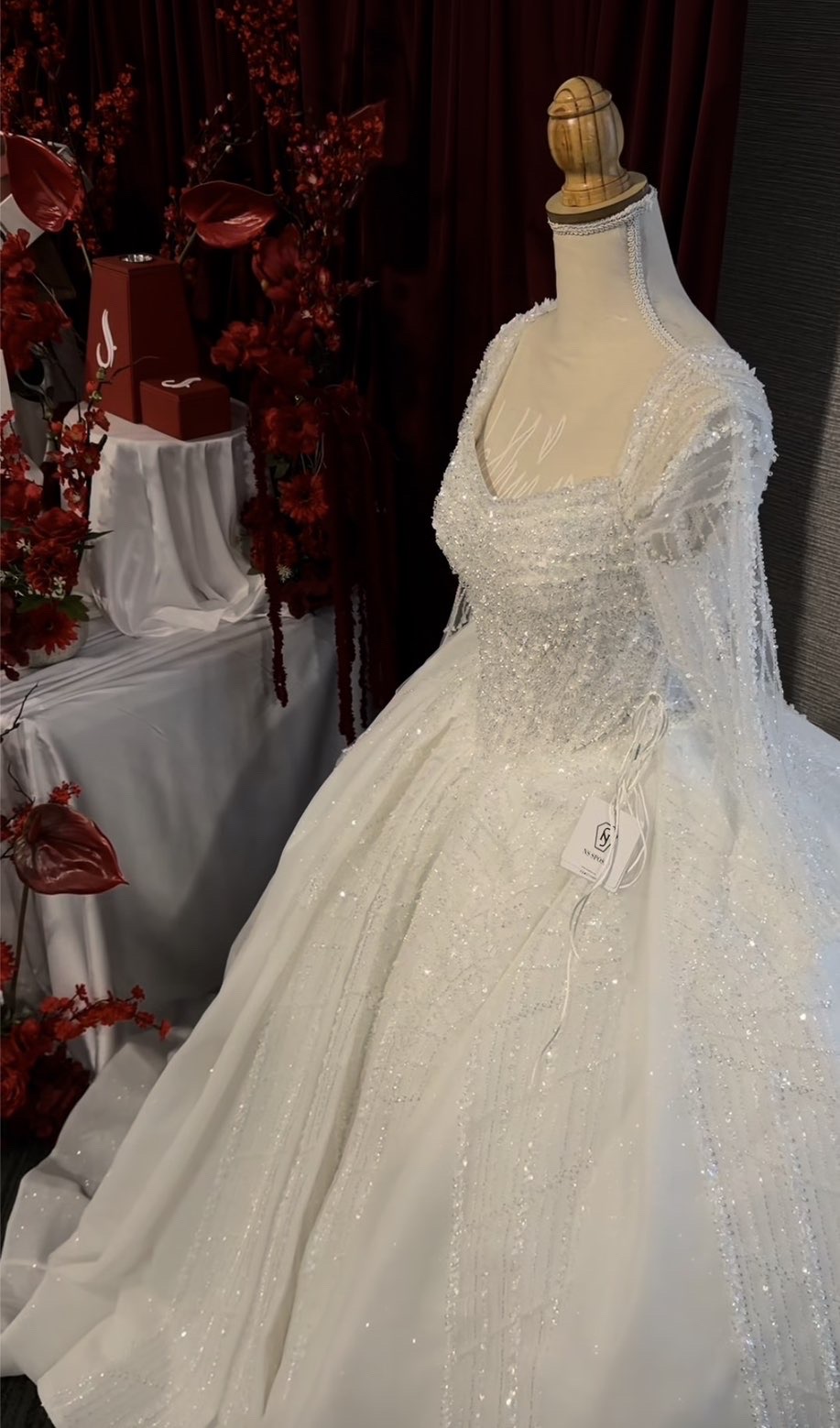Beaded white bridal gown with a long veil on a dress form